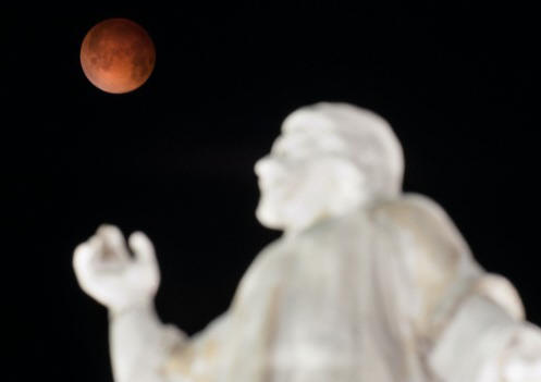 A "blood moon" rises over the El Salvador del Mundo monument in San Salvador early Tuesday, April 15, as a total lunar eclipse attracts sky gazers across the Americas. In a total lunar eclipse, the full moon turns a coppery red as it passes into Earth's shadow. North America will see a blood moon four times -- known as a tetrad -- between now and September 2015.